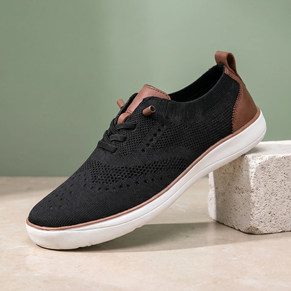 Black knit lace-up shoe with a white sole on a limestone block