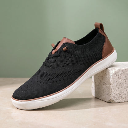 Black knit lace-up shoe with a white sole on a limestone block