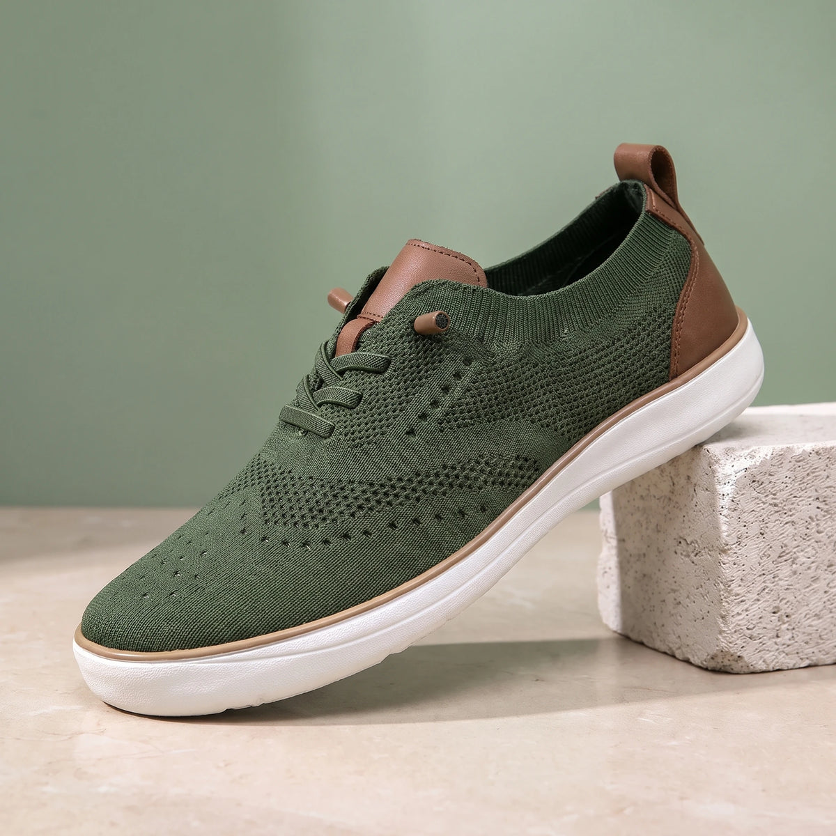 Green knit lace-up shoe with a white sole on a limestone block
