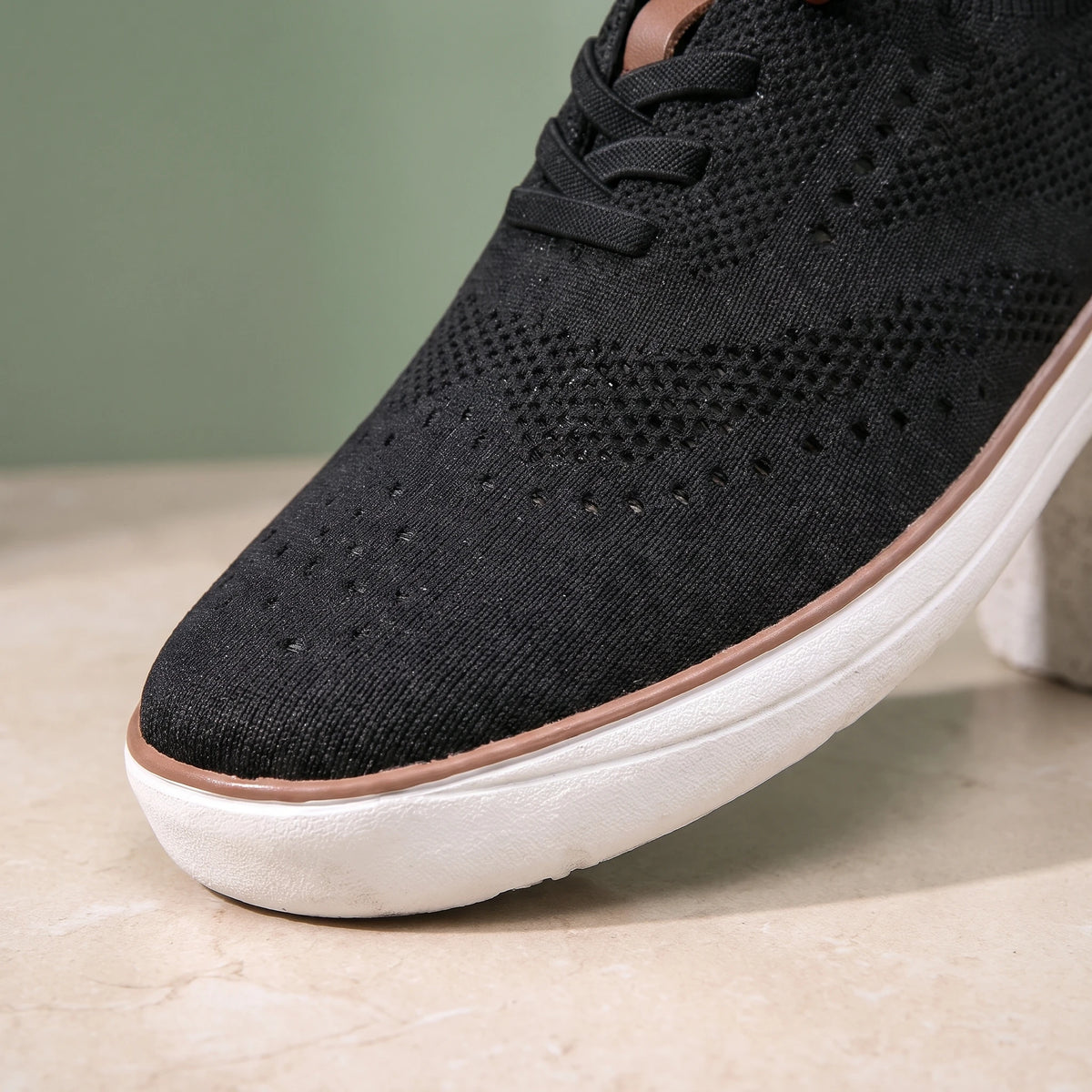 Close-up of the perforated toe of the black knit shoe