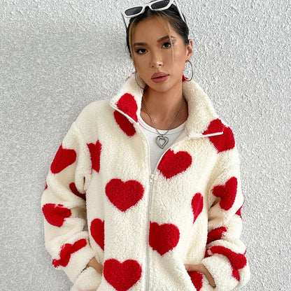 Person wearing a white fleece jacket with red heart patterns on a textured gray background